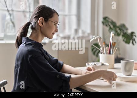 Artista di ceramica asiatica seduto a tavola Foto Stock