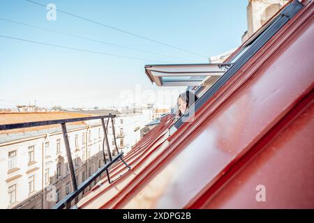 fuga, prospettiva mentre la donna guarda fuori dalla finestra dell'attico sul paesaggio urbano Foto Stock