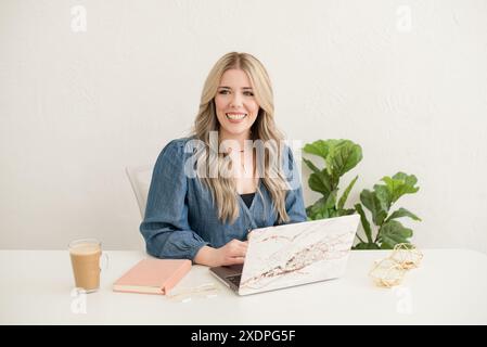 Donna sorridente che lavora su un notebook in ufficio Foto Stock