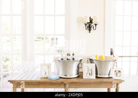 Postazione bevande con bottiglie di champagne e succo in secchi di ghiaccio Foto Stock