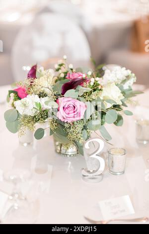 Elegante centro matrimoni con rose e verde su un tavolo Foto Stock