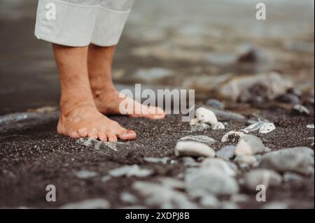 I piedi della donna nella sabbia vicino al fiume, in un ambiente sereno e naturale Foto Stock