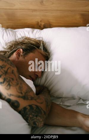 Un giovane uomo dorme dolcemente a letto. Foto Stock