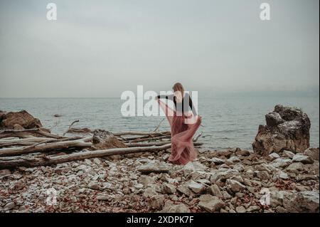 Donna che danzava in un abito fluente sul lago Thun, in Svizzera, in inverno Foto Stock