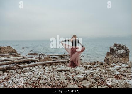 Donna che danzava in un abito fluente sul lago Thun, in Svizzera, in inverno Foto Stock