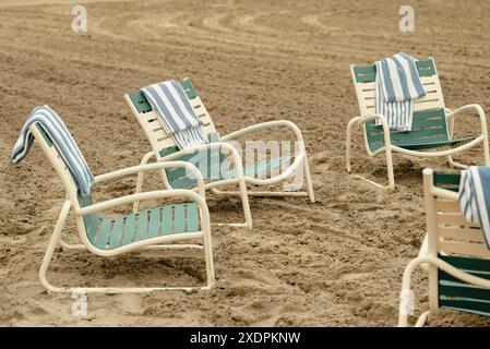 Sedie a sdraio con asciugamani a righe sulla spiaggia sabbiosa Foto Stock