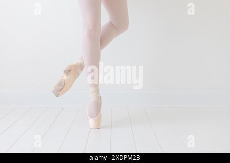 primo piano dei piedi della ballerina in pointe in uno studio bianco Foto Stock