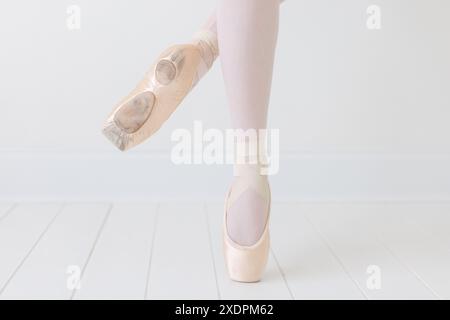 primo piano dei piedi della ballerina in pointe in uno studio bianco Foto Stock