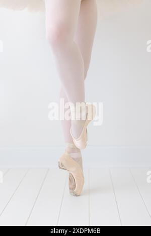 primo piano verticale dei piedi della ballerina in pointe in uno studio bianco Foto Stock