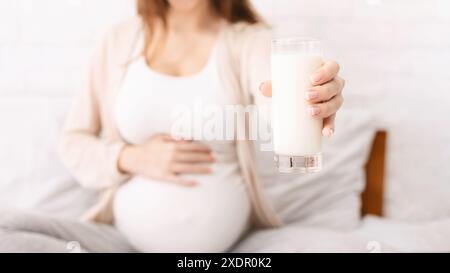 Donna incinta che offre un bicchiere di latte fresco con la macchina fotografica Foto Stock