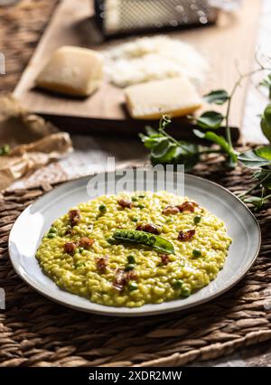 Risotto allo zafferano italiano con piselli e pancetta serviti in modo creativo su un piatto. Foto Stock