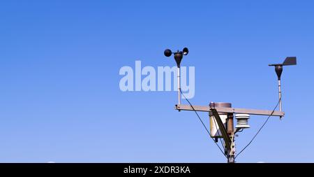 Primo piano di un anemometro per misurare la velocità del vento, una piccola stazione meteorologica. Anemometro su sfondo blu, copia spazio Foto Stock