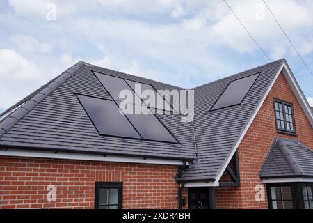 Una casa di nuova costruzione nel Regno Unito con pannelli solari installati sul tetto. Celle solari fotovoltaiche su edifici residenziali. Fonte energetica sostenibile Foto Stock