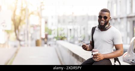 Uomo con caffè e telefono in ambiente urbano Foto Stock