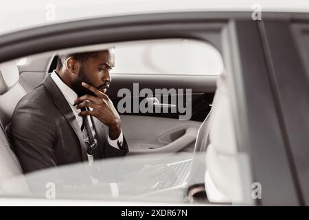 Uomo d'affari che lavora su un notebook sul sedile posteriore dell'auto Foto Stock