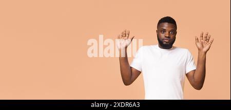 Uomo con le mani sollevate davanti allo sfondo arancione chiaro Foto Stock