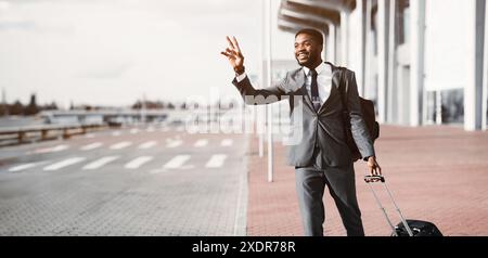 Prendi il taxi. Un uomo d'affari afro che chiama un taxi all'aeroporto Foto Stock