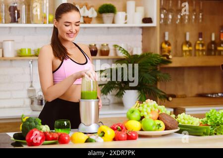 Donna che fa il succo sano con la macchina in cucina Foto Stock