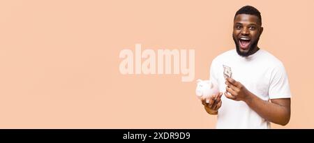 Uomo che detiene Cash e Piggy Bank su Peach background Foto Stock