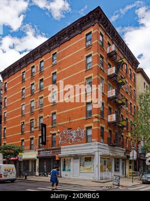 Chinatown di New York: 56 Hester Street è un edificio di appartamenti a sei piani in mattoni arancioni con negozi, circondato da campi da banda di pietra. Foto Stock