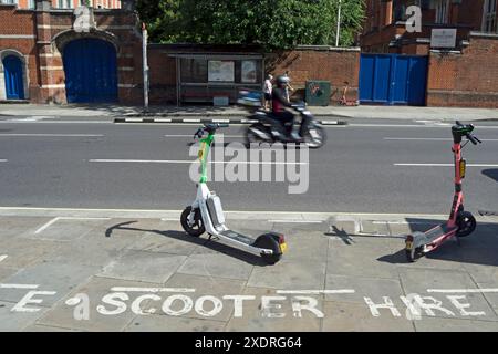 due e-scooter sul marciapiede contrassegnati per il parcheggio di scooter elettrici a noleggio, a hammersmith, londra, inghilterra Foto Stock