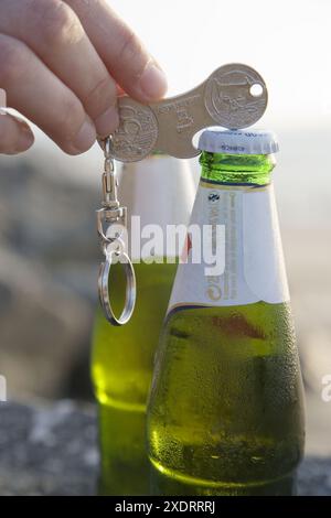 Apertura della bottiglia di birra utilizzando moneta a forma di anello chiave dispositivo Foto Stock