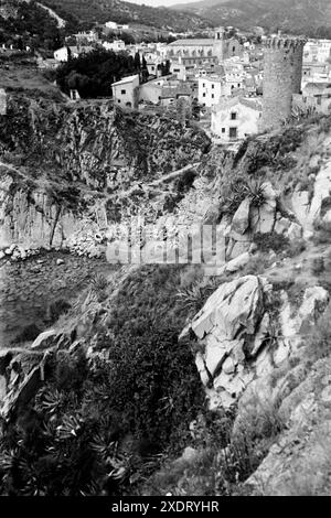 Blick auf Tossa de Mar, rechts einer der Türme der alten Stadtmauer, im Hintergrund die Pfarrkirche Sant Vincenj, in der Mitte eine kleine felisge Bucht, in der Fischerboote am Strand liegen, Katalonien 1957. Vista di Tossa de Mar, sulla destra una delle torri delle mura della città vecchia, sullo sfondo la chiesa parrocchiale di Sant Vincenj, al centro una piccola baia rocciosa con barche da pesca sulla spiaggia, Catalogna 1957. Foto Stock