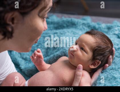 Una madre amorevole si prende cura del suo bambino appena nato a casa. Brillante ritratto di una madre felice che tiene in braccio un bambino. La madre abbraccia il suo figlioletto. Foto Stock