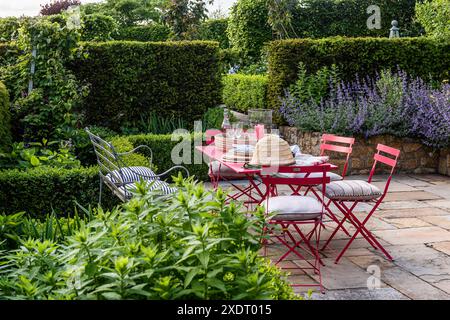 Sedie rosse pieghevoli al tavolo sulla terrazza giardino della canonica del Somerset risalente al XVII secolo, Inghilterra sud-occidentale, Regno Unito Foto Stock