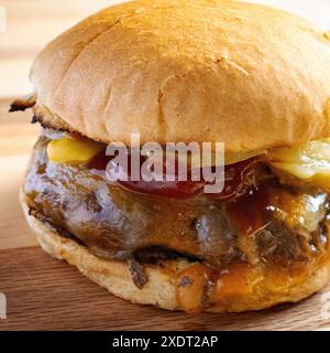 Direttamente dalla griglia, hamburger con formaggio cojack, cipolle grigliate, sottaceti di aneto, ketchup e senape su un panino tostato. Su un boa di legno Foto Stock