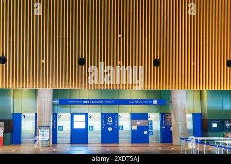 Nucleo centrale di sei ascensori su una parete della Glass Hall nel Tokyo International Forum in serata. Sopra di loro la caratteristica parete in legno. Foto Stock