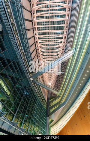 Vista verticale grandangolare lungo l'interno dell'edificio del Tokyo International Forum in serata, che mostra il piano principale e il tetto in alto. Foto Stock