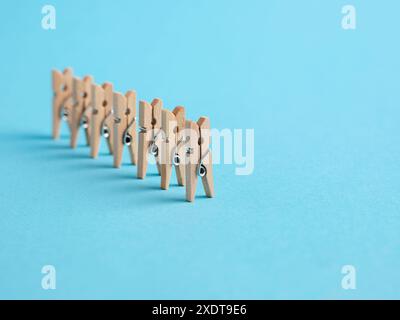 Concetto di leadership. Follower o attività successiva. clothespin in miniatura in legno in fila su sfondo blu. Foto Stock