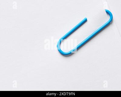 Graffetta blu attaccata alla pila di carta bianca bianca bianca. Vista a layout piatto e ravvicinato con spazio di copia. Foto Stock
