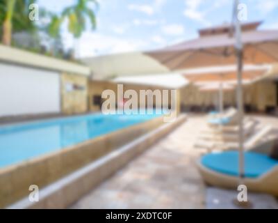 Sfocatura astratta di una lunga piscina all'aperto, ombrelloni e lettini all'hotel del resort senza nessuno, per sfondo e carta da parati. Vista sfocata di Foto Stock