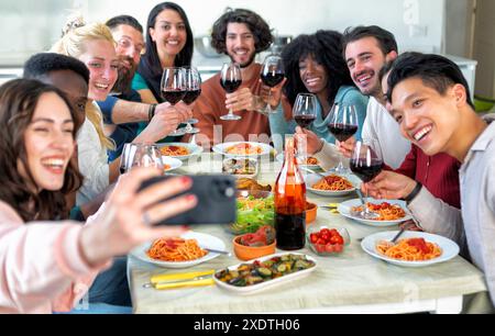 gruppo di giovani amici che festeggiano a casa mangiando e bevendo alcolici mentre fanno un selfie Foto Stock