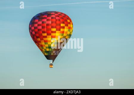 Pallone colorato ad aria calda in volo completo con un cielo blu sullo sfondo. Foto Stock