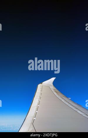 Ala di un moderno jet passeggeri in volo isolato contro un cielo blu profondo. Niente persone. Copia spazio. Concetto di viaggio. Foto Stock