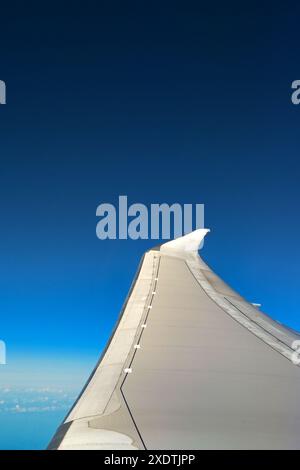 Ala di un moderno jet passeggeri in volo isolato contro un cielo blu profondo. Niente persone, Copia spazio. Concetto di viaggio. Foto Stock