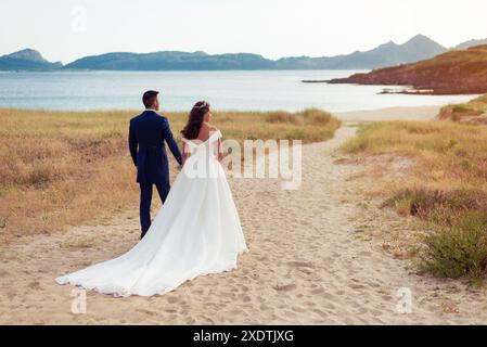 Sposa e sposo che contemplano una spiaggia dopo il matrimonio Foto Stock