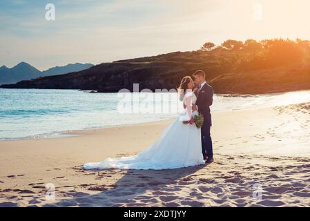 Sposa e sposo che si contemplano a vicenda su una spiaggia dopo il matrimonio Foto Stock