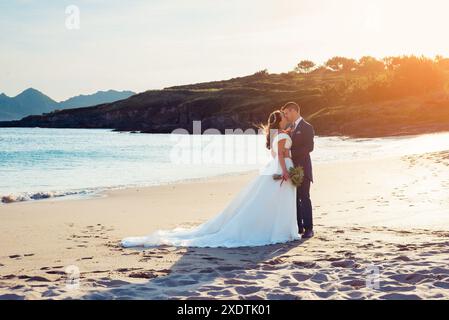 Sposa e sposo che si contemplano a vicenda su una spiaggia dopo il matrimonio Foto Stock