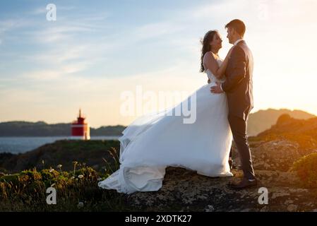 Sposa e sposo che si contemplano l'un l'altro vicino a un faro dopo il matrimonio Foto Stock