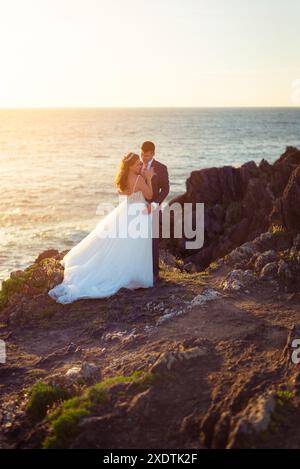 Sposa e sposo che si contemplano l'un l'altro su una scogliera dopo il matrimonio Foto Stock