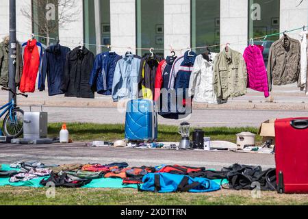 Abiti usati in vendita appesi alla clothesline al mercato delle pulci pop-up all'aperto del parco Dallapé nel quartiere Vallila di Helsinki, Finlandia Foto Stock