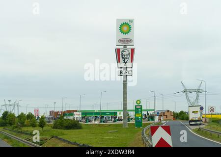 Poznan, Polonia - 19 maggio 2023: Un'insegna torreggiante include i loghi per BP e KFC accanto a un'autostrada, con edifici commerciali e cieli rovesciati nella ba Foto Stock