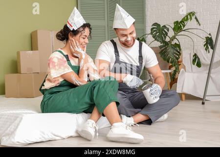 Bella giovane coppia felice che apre lattina di vernice mentre fa la riparazione nella loro nuova casa Foto Stock