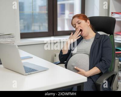 Donna incinta che dorme alla sua scrivania in ufficio. Foto Stock