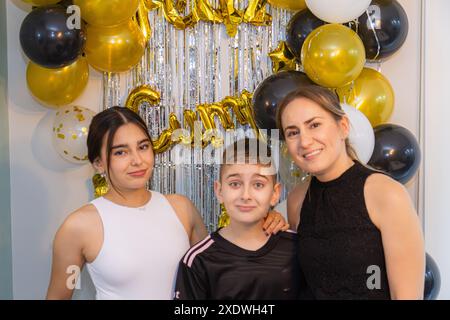 Giovane ragazza di compleanno accompagnata dal suo fratellino e dalla madre. Foto Stock