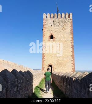 Persona caucasica che cammina verso una delle torri militari all'interno del muro di Molina de Aragon. Guadalajara. Foto Stock